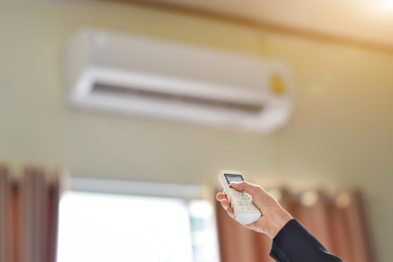 zbliżenie na rękę trzymającą pilota sterującego klimatyzatorem